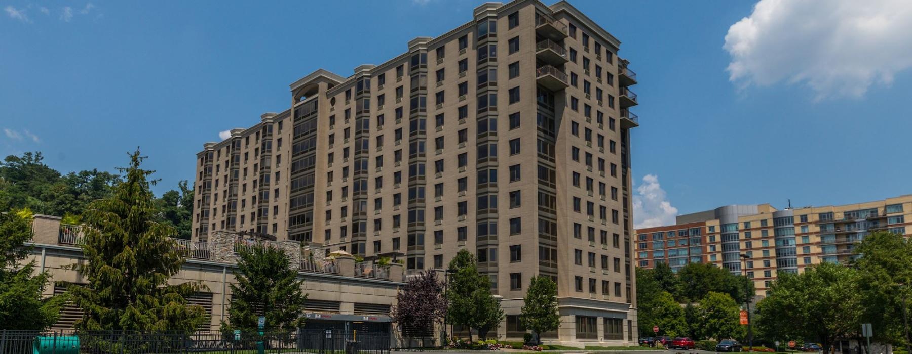 a large building with trees in front of it with Fisher Building in the background